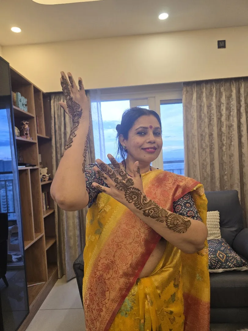 Seema in a yellow saree showing henna designs on both arms