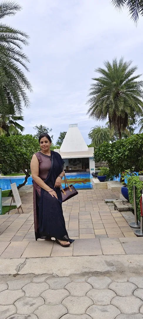 Seema outdoors beside a pool under palm trees